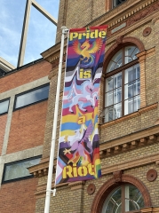 Eine Prideflagge vor der Universität für angewandte Kunst Wien. Darauf zu sehen ist ein Einhorn, ein Hippogreif
                                          und ein Phönix. Im Hintergrund gehen regenbogen-farbene Streifen ineinander über.