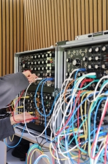 Eine Hand hantiert an einem Gerät mit vielen Kabeln im ÆSR Lab im Rahmen der Langen
                                          Nacht der Forschung 2026 