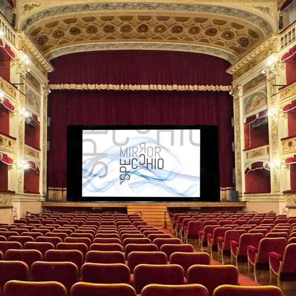 A theatre auditorium with red chairs and a screen bearing the word 