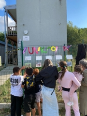 Teilnehmerinnen der Summer School stehen an einem Zaun, an dem bunte Buchstaben und Zetteln
                                          haengen
