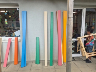 Ein Junge geht an einem Gebäude vorbei an dem bunte Holzlatten lehnen