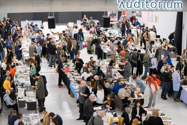 Atrium der Universität für Angewandte
                                          Kunst Wien während der Art Book Fair, gefüllt mit Menschen und Messeständen