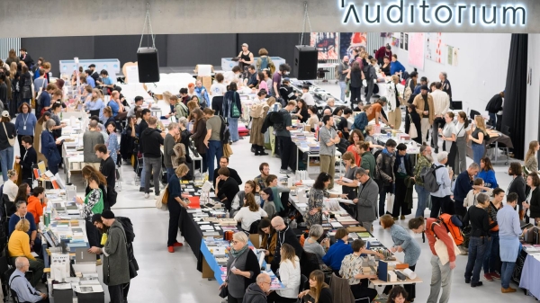 Atrium der Universität für Angewandte Kunst Wien während der Art Book
                                          Fair, gefüllt mit Menschen und Messeständen