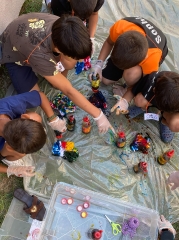 Kinder sitzen auf einer Plane mit Farbflaschen