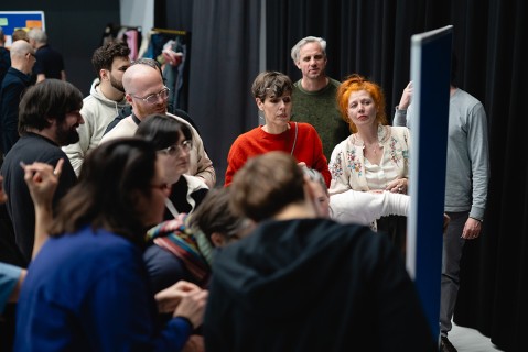 Eine Gruppe Menschen steht um ein Plakat bei einem Workshop