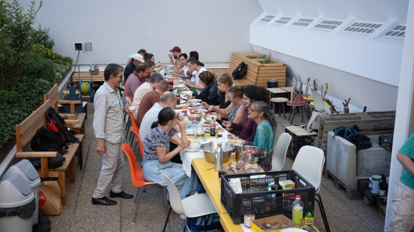 Foto einer Gruppe von Menschen an einem langen
                                          Tisch gefüllt mit Essen.