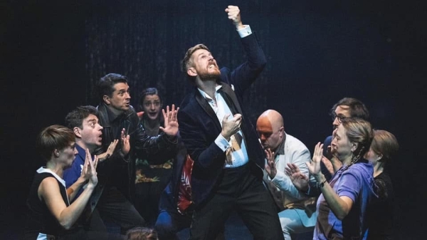 Performer Jim Libby auf einer Bühne mit anderen
                                          Schauspielern