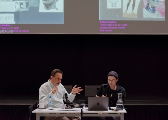 Richard Hawkins im Gespräch mit Christian Liclair
                                          an einem Tisch in einer Eventhalle