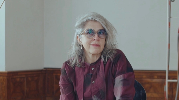 The artist Leonor Antunes sitting in her exhibition