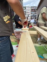 Ein Handwerker streicht eine Holzlatte 