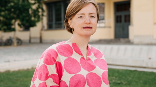 Color portrait by Ulrike Kuch in front of a green meadow with a building in the background