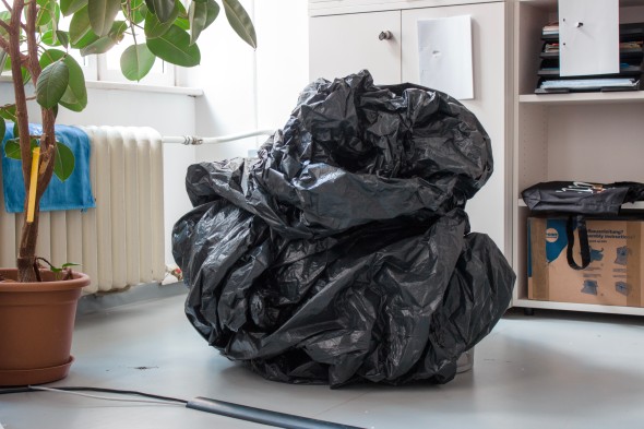 Performance von Arina Nekliudova / Performerin in schwarzem übergroßem Müllbeutel