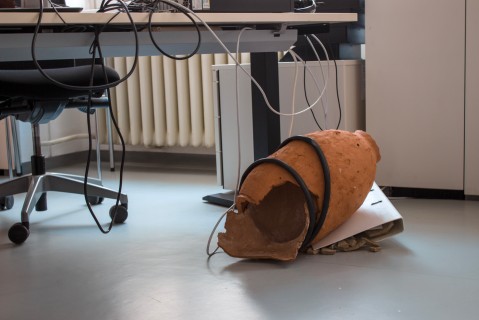 Work by Alina Izmailova / A broken clay vase sitting on a folder on the floor