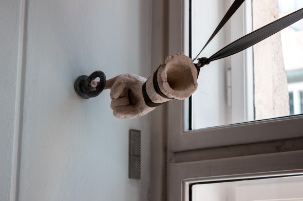 Arbeit von Rikki Winde / Eine Tonhand in einem Haken, freischwebend, gehalten von Hosenträgern