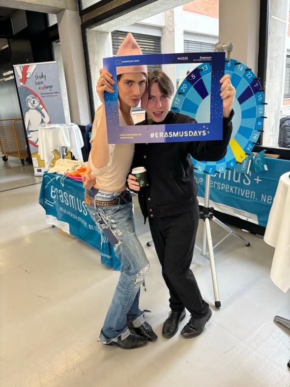 Zwei Studierende vorm Stand in lustiger Pose