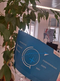 The Erasmus+ flag in the foreground, the offices of the International Office in the background.